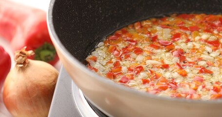 Onions with paprika or sweet pepper are fried in a pan with bubbles of oil. Cooking bolognese sauce. Food preparation in the kitchen. A series of photos to visualize the recipe.