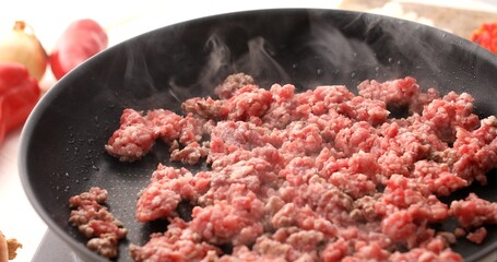 Raw Minced meat is fried in a pan with steam. Cooking bolognese sauce. Food preparation in the kitchen. A series of photos to visualize the recipe.