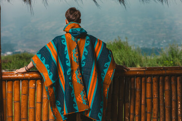Model wearing a poncho handmade with sheep cloth by the indigenous Kichwa artisan communities of the area, posing at the San Pablo lake in Otavalo, Ecuador.