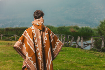 Model wearing a poncho handmade with sheep cloth by the indigenous Kichwa artisan communities of the area, posing at the San Pablo lake in Otavalo, Ecuador.