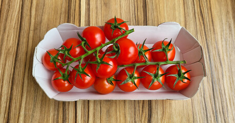 A bunch of fresh red tomatoes with green stalks in a box
