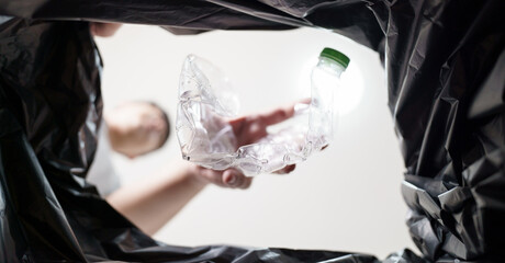 Image from inside yellow recycling bag of man throwing empty plastic bottle in recycling bin Home recycle eco green zero concept.