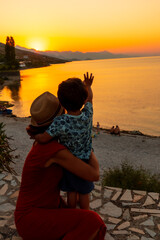 Mother and son saying goodbye to the sun at sunset at Shkoder lake in Shiroka municipality, summer vacation. Albania