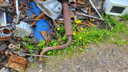 Scrap yard with old iron and sheet metal from cars, appliances, shelves, tin rails and corrugated metal roofing.