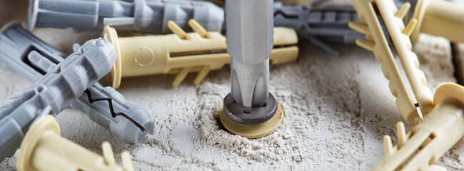 screwdriver screw and dowel in a concrete wall background