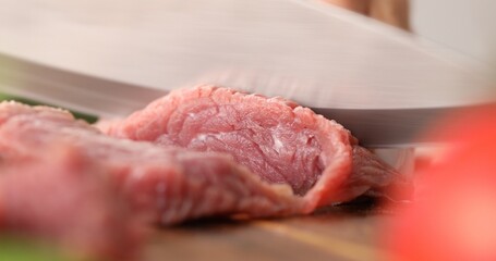 Cutting raw meat. Female hands cut fresh beef on a wooden chopping board. Cooking in the kitchen. Food preparation.