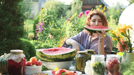 Beautiful woman eating watermelon while sitting at the table in her summer cottage on a sunny day