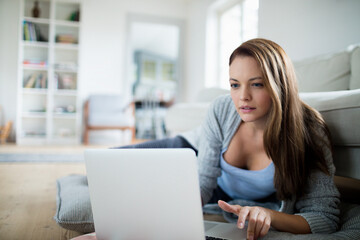 Young woman using a laptop in the living room at home