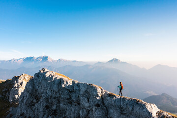 Mountaineering on the mountain, a young woman hiking on the trail with trekking poles on the top of...