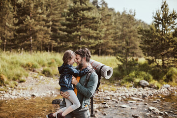 Fototapeta na wymiar Young father hiking with his daughter in a forest