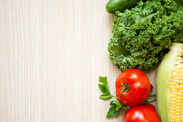 Fresh vegetables on wood background. Aromatic herbs, corn, cucumber, tomatoes, kale, leaf cabbage
