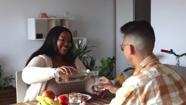 happy multiracial couple eating together at home in dining room