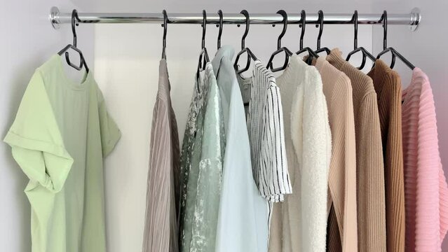 Woman organizing clothes in wardrobe. Closet organization and decluttering routine. Minimalist wardrobe with neutral clothing. Organized closet and home storage concept.