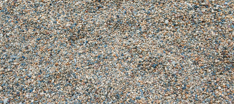 Background and texture of a heap of small pebbles. Panorama.