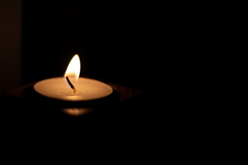 Close-up of flame burning on candle isolated on a black background. - Center Left