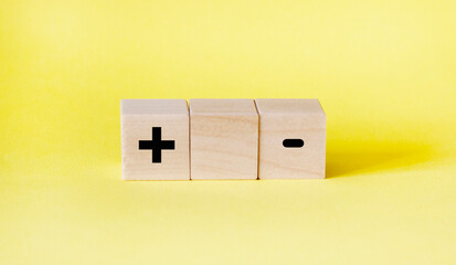 blocks on a yellow background with a plus and a minus. Choice concept