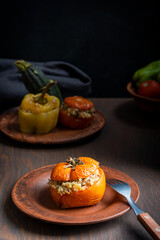 Homemade juicy organic tomato stuffed with rice and baked until soft served on plate with fork on dark brown wooden table as part of gemista traditional greek recipe of filled roasted vegetables