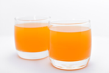 Glass glasses with orange juice on a white background. Delicious orange cooling drink.