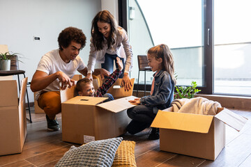 Mixed race family moving into their new home. They're unpacking and having fun together.
