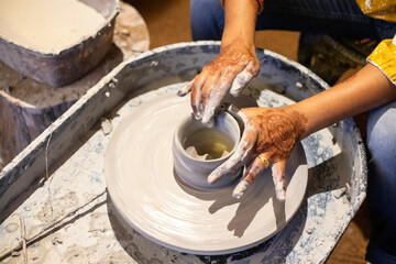 A female learning pottery using clay on potter's wheel