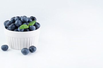 On a white background, with space for writing a text, a plate with blueberries. Healthy food concept.