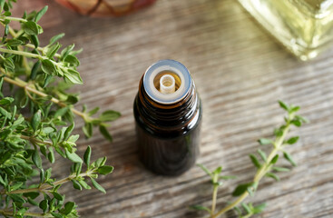 A bottle of thyme essential oil with fresh thyme