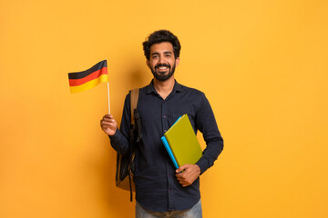 Education Abroad. Portrait Of Happy Young Indian Student Guy Holding German Flag