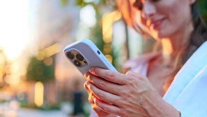 Close up of woman texting, scrolling on smartphone, reading news, searching information in internet outdoors. Background of big city with skyscrapers. Freedom and active lifestyle concept.