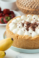 Banoffee cake with banana and caramel sauce filling sprinkled with grated dark chocolate on the white marble background. Flat lay. English traditional pie