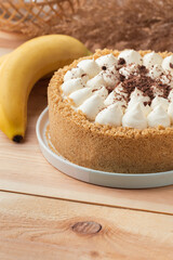 Banoffee cake with banana and caramel sauce filling sprinkled with grated dark chocolate on the wooden rustic background. English traditional pie