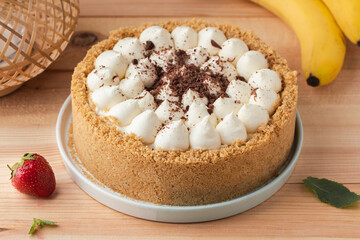 Banoffee cake with banana and caramel sauce filling sprinkled with grated dark chocolate on the wooden rustic background. English traditional pie