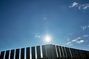 blue sky, bright sun, fence in the countryside