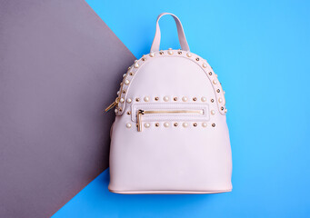 Trendy white leather women's backpack with a zipper decorated with gold metal and pearl rivets...
