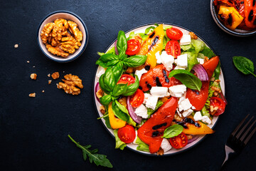 Fresh healthy salad with grilled paprika, feta cheese, walnut, red onion, green basil and mixed...