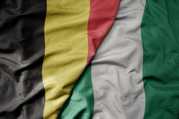 big waving national colorful flag of belgium and national flag of nigeria .