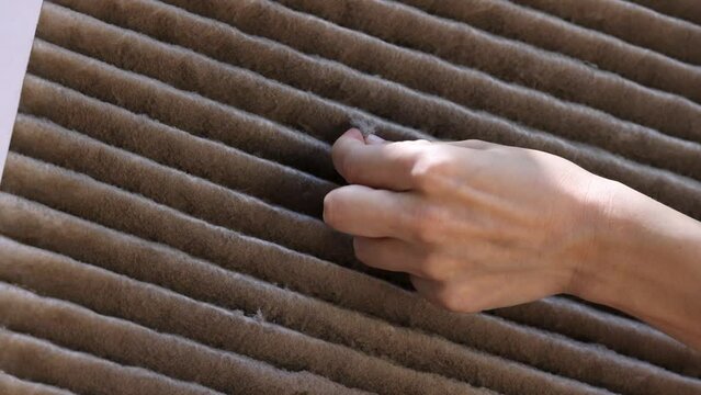 Hands pick up dust from dirty and clogged house AC filter. Concept of air quality inside home and the need to replace old filters
