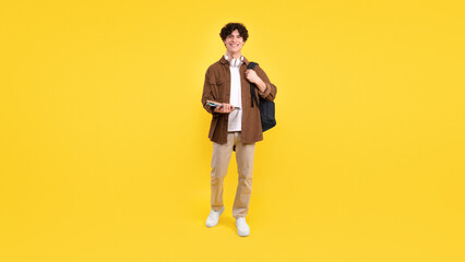 Guy student with backpack and bunch of notebooks standing, studio