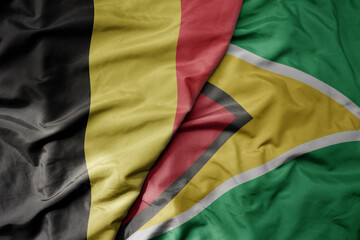 big waving national colorful flag of belgium and national flag of guyana .