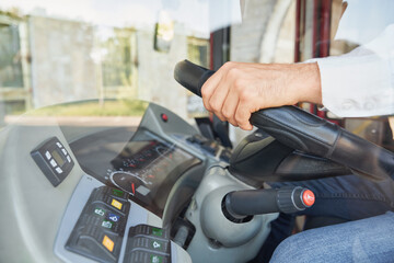Unrecognizable man wearing shirt driving intercity bus at daytime. Crop view of male professional bus driver steering wheel at work. Concept of transportation, work place.