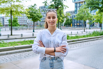 Portrait of teenage girl with crossed arms on street of city