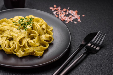 Delicious fresh pasta with pesto sauce, salt, spices and herbs on a ceramic plate