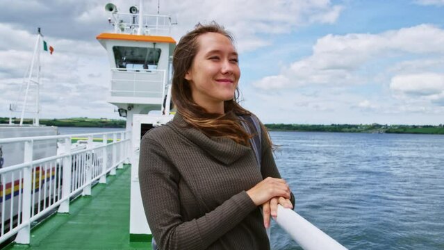 Woman on ferry looking out at sea, close up smile 