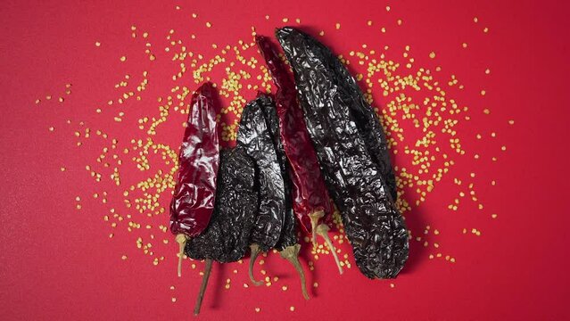 Placing a group dried mexican chili on red surface with seeds