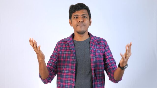 A young man angry and asking why in front of camera plain background