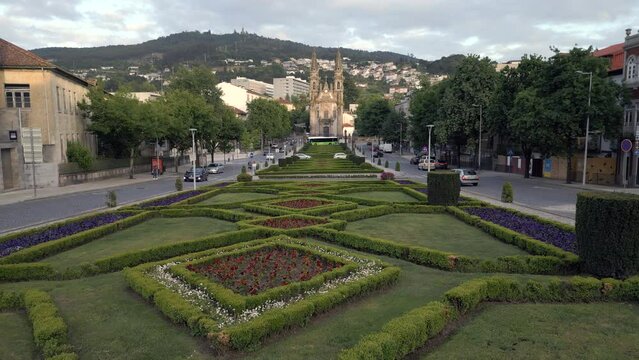 Dolly left shot showing beautiful gardens in front of the historic Nossa Senhora da Consolacao e Santos Passos church (aka Sao Gualter church) in Guimaraes, Portugal.	
