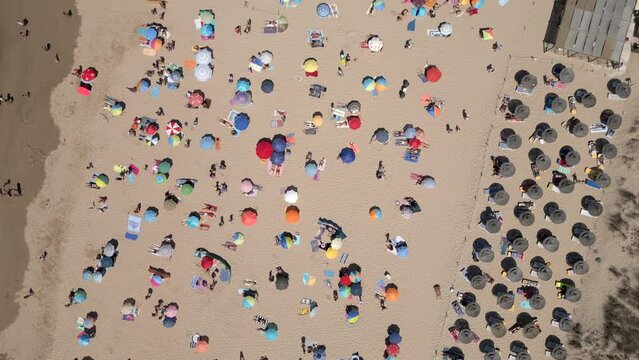 Top down aerial view of people enjoying summer at the beach in Costa da Caparica, near Lisbon, Portugal.