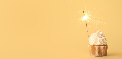 Tasty cupcake with sparkler on beige background with space for text