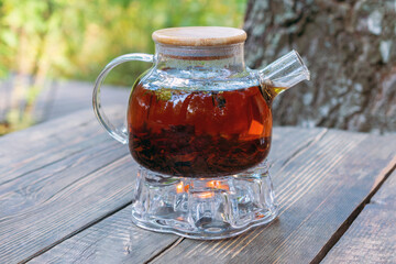 Glass teapot heated by a candle. Drinking tea outside the city