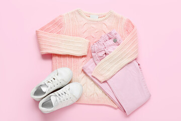 Stylish children's sweater, pants and shoes on pink background