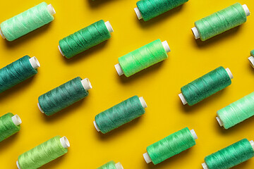 Composition with colorful thread spools on yellow background